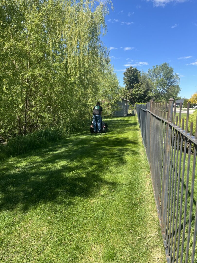 A person riding a scooter on top of grass near a fence.